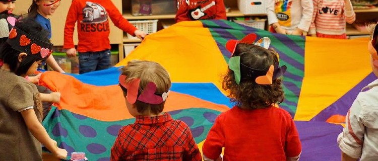 toddlers with parachute indoors at Children's Garden Nursery School in Toronto
