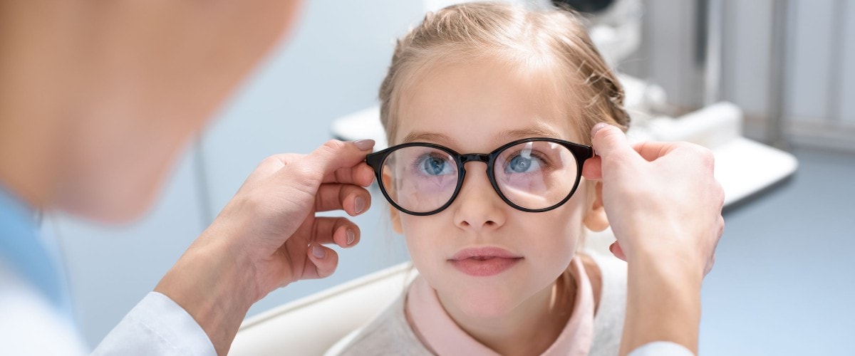 girl being fitted for glasses by optometrist