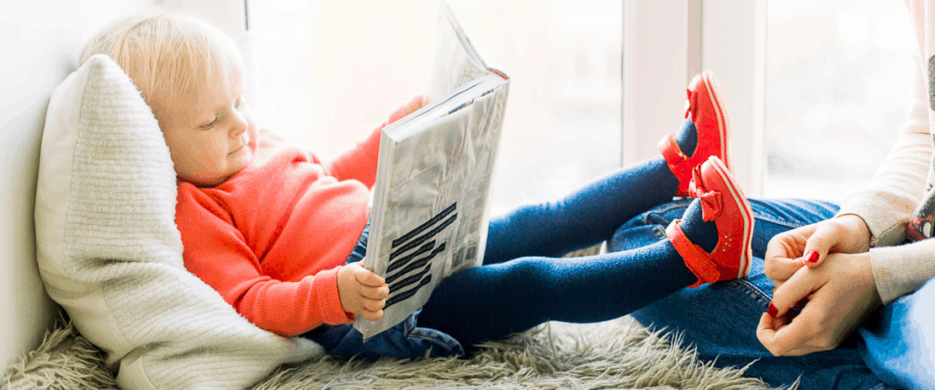 Child reading book by the window