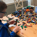 Child building with Lego in front of tablet