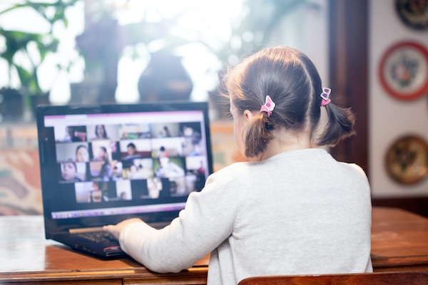 girl looking at group Zoom call on a laptop