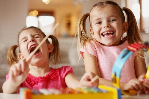 Toddler girls playing tambourine and xylophone at home