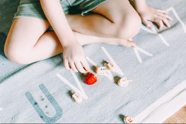 child playing with dreidels on carpet