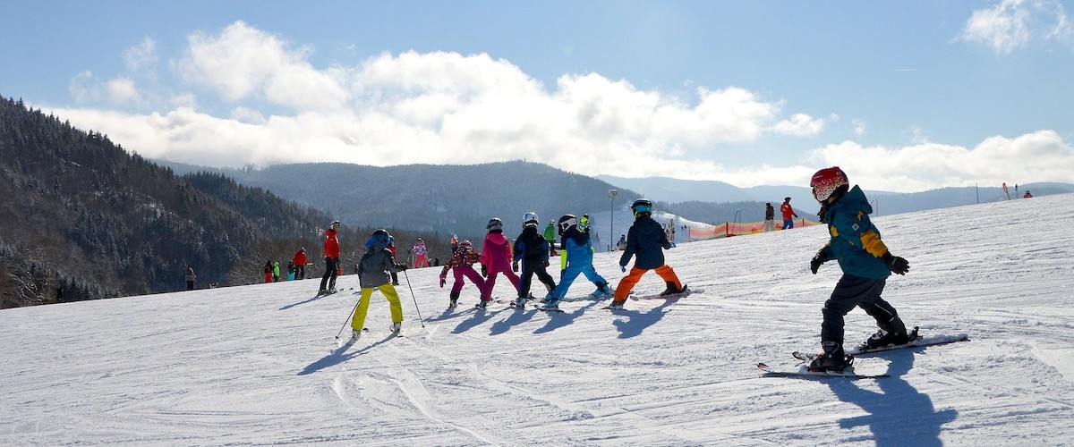 group of young kids getting a ski lesson on a ski hill with instructor