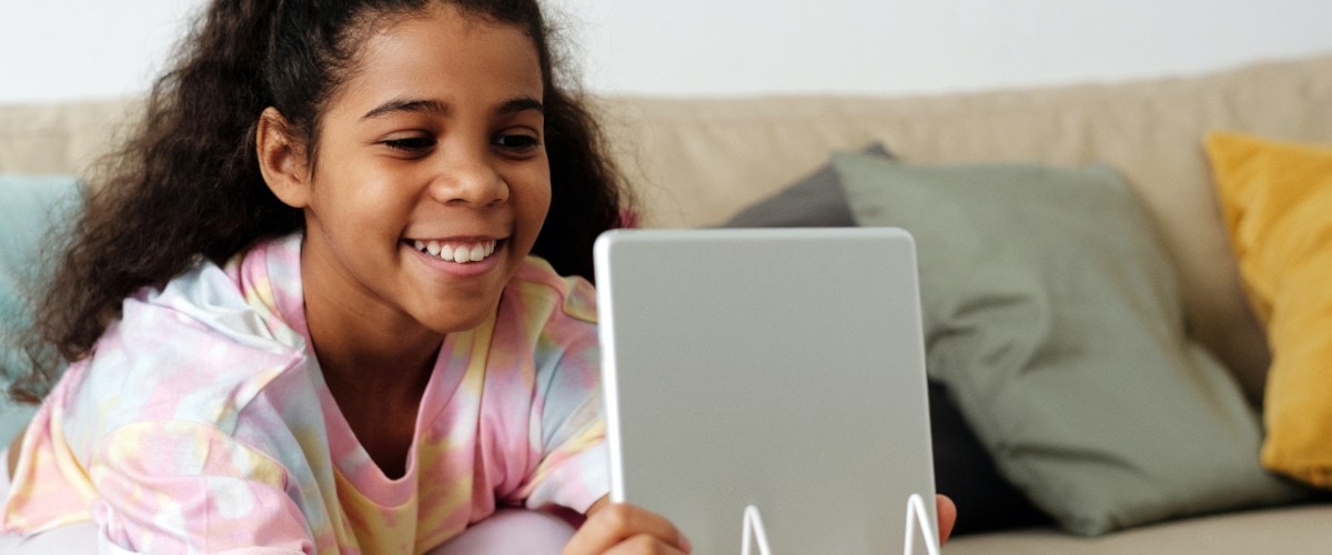girl at home smiling and looking at tablet