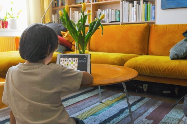 child playing online chess on tablet in living room