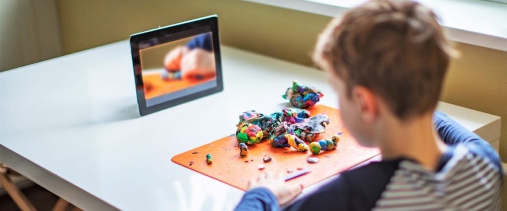 child building with clay at home and watching tablet